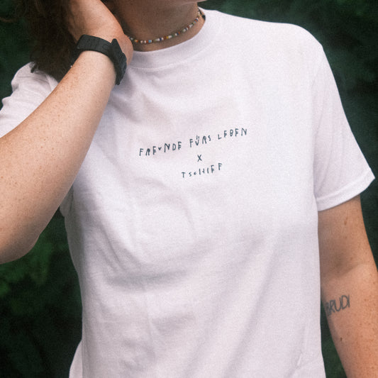 Detail vorn: weißes T-Shirt mit kleinem schwarzen Brustprint „FREUNDE FÜRS LEBEN × TSCHIFF“.