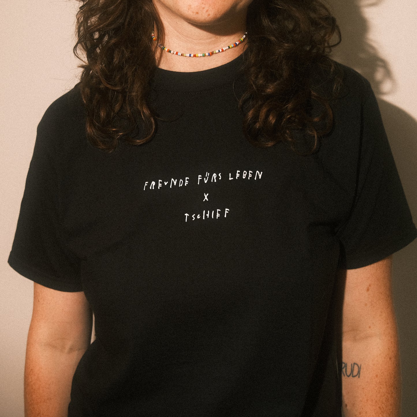 Detail vorn: schwarzes T-Shirt, mittiger Schriftzug in Weiß „FREUNDE FÜRS LEBEN × TSCHIFF“.