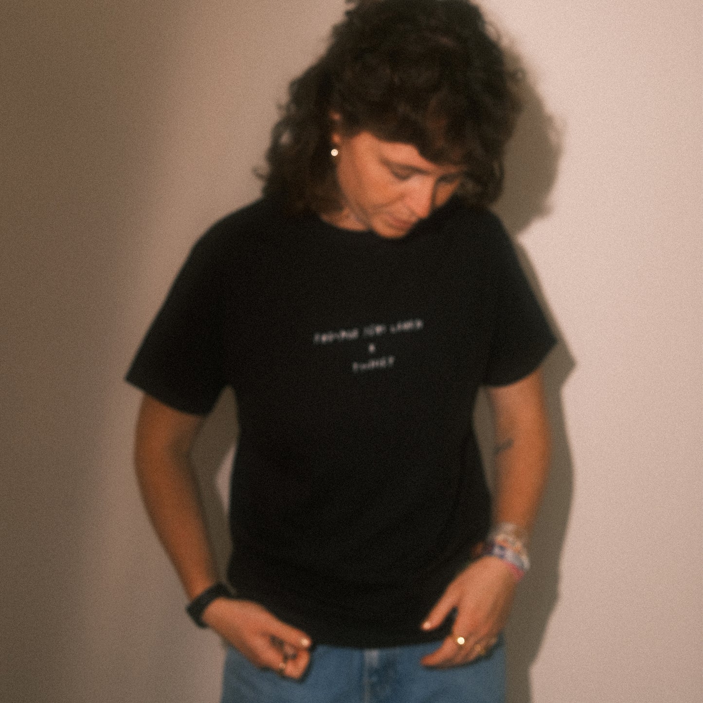 Weich unscharfe Frontansicht: schwarzes T-Shirt mit kleinem weißen Brustprint (Schriftzug), Regular-Fit.