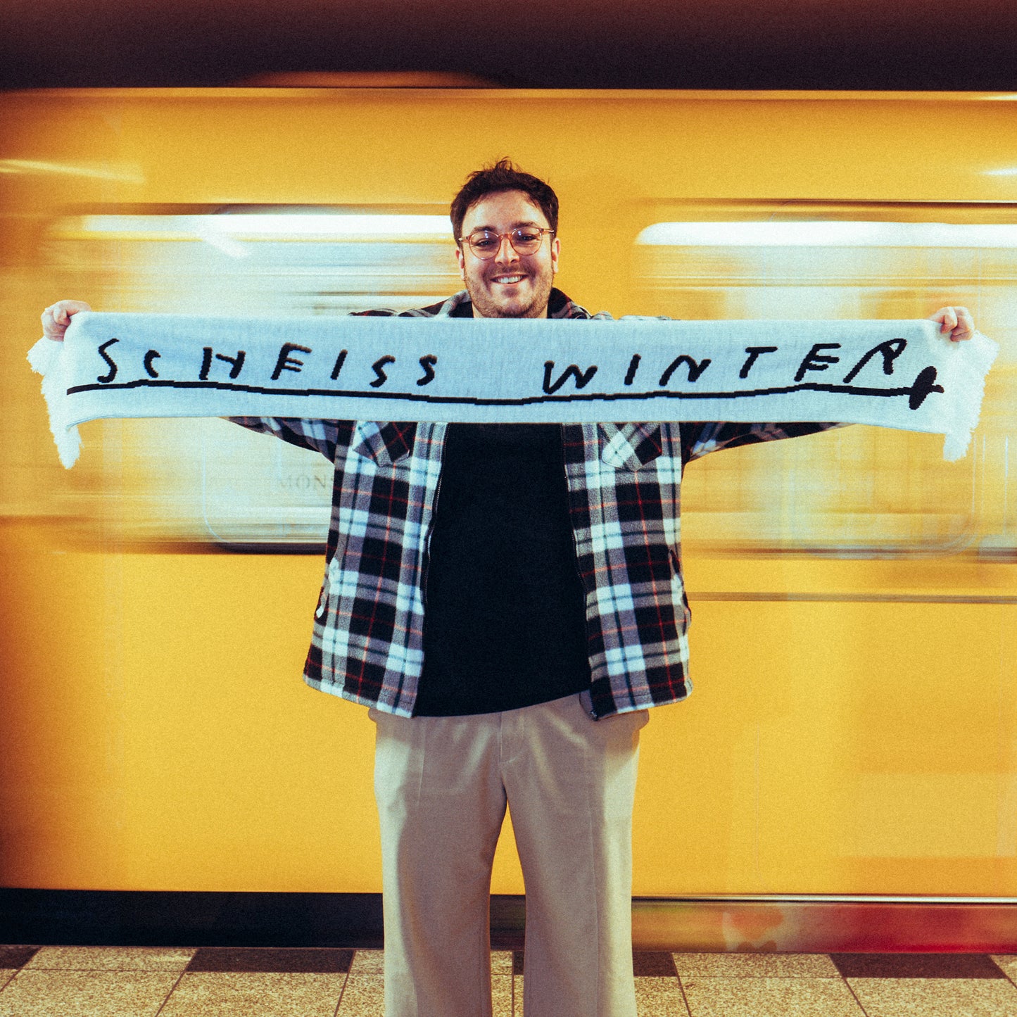 Weißer Fanschal mit schwarzem Schriftzug „SCHEISS WINTER“ in handschriftlichem Stil