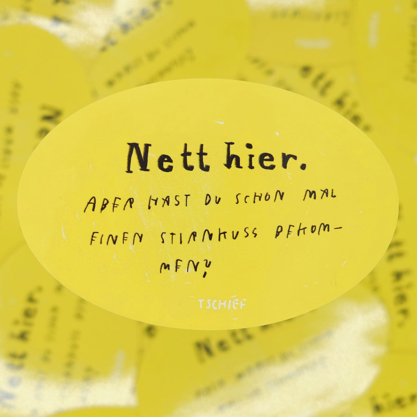 Gelber ovaler Aufkleber mit schwarzer und weißer Schrift. Oben steht in großer Schrift „Nett hier.“ Darunter in handschriftlicher Schrift: „Aber hast du schon mal einen Stirnkuss bekommen?“ Unten mittig steht klein „TSCHIEF“.