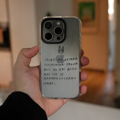 Nahaufnahme einer transparenten Handyhülle mit schwarzer Handschrift. Auf der Hülle steht:
„Selbst an deinen schlechten Tagen bist du das Beste, was ich je kennengelernt habe.“
Darüber sind zwei kleine, minimalistische Figuren, die sich an den Händen halten, gezeichnet.