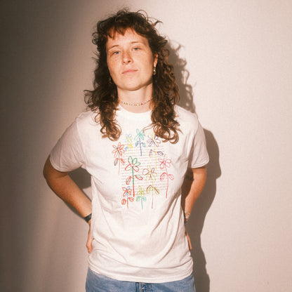 Studio-Frontansicht: weißes T-Shirt mit farbigem Blumenmotiv, gerader Schnitt, kurze Ärmel.