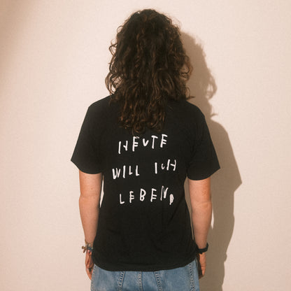 Studio-Rückenansicht: schwarzes T-Shirt, großflächiger weißer Text „HEUTE WILL ICH LEBEN“.