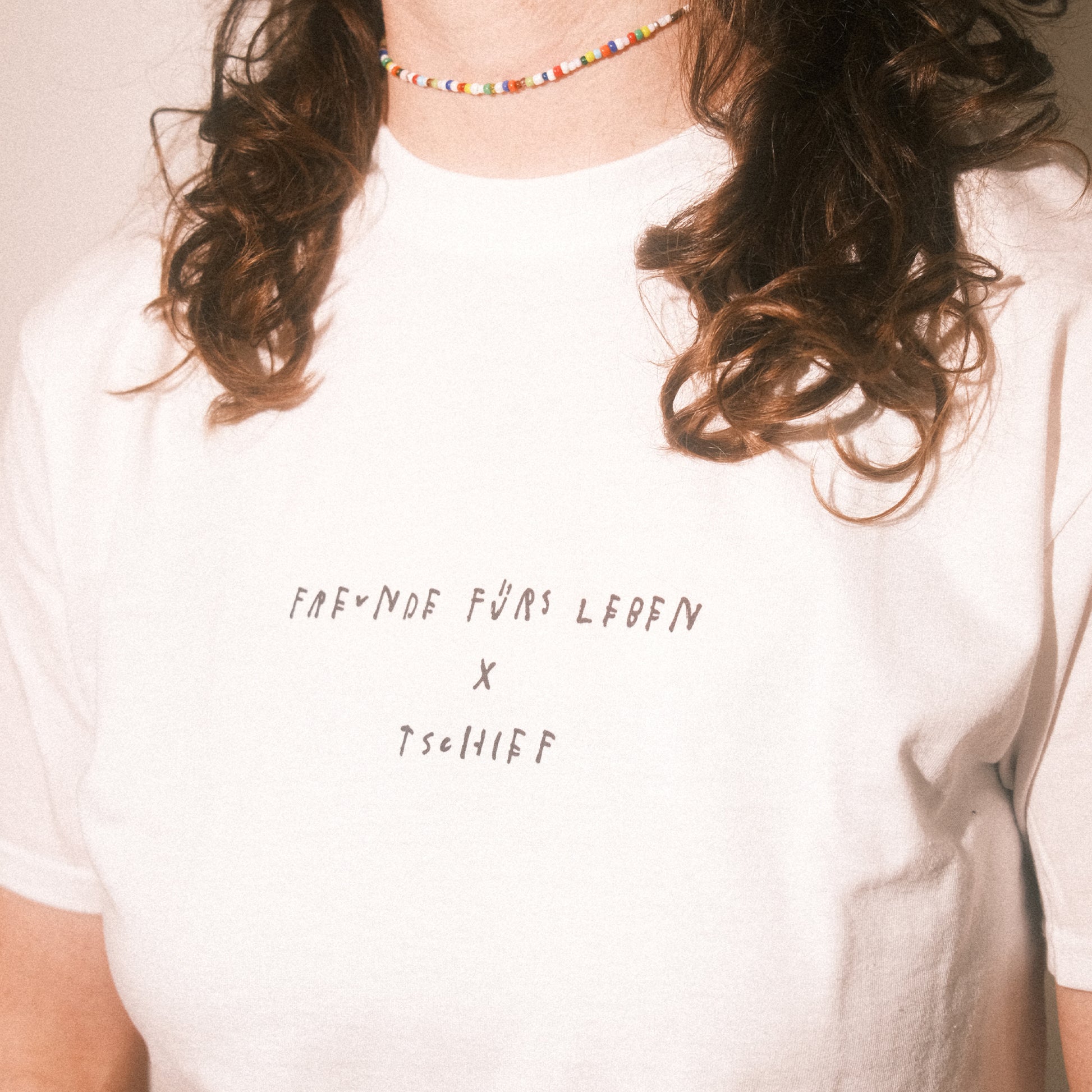 Nahaufnahme Brust: klar lesbarer Schriftzug „FREUNDE FÜRS LEBEN × TSCHIFF“ auf weißem T-Shirt.