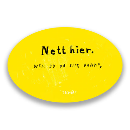 Gelber, ovaler Aufkleber mit schwarzem Schriftzug „Nett hier.“ Darunter handschriftlich ergänzt in Schwarz „Weil du da bist, danke.“ Unten steht klein „TSCHIEF“. Der Hintergrund ist weiß.