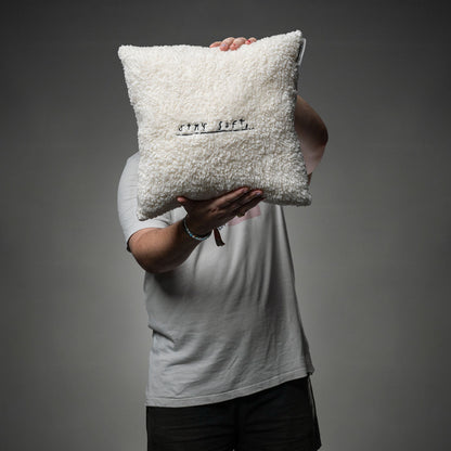 Das weiche, cremeweiße Kissen mit schwarzer Stickerei „STAY SOFT,“