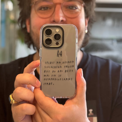 Nahaufnahme einer transparenten Handyhülle mit schwarzer Handschrift. Auf der Hülle steht:
„Selbst an deinen schlechten Tagen bist du das Beste, was ich je kennengelernt habe.“
Darüber sind zwei kleine, minimalistische Figuren, die sich an den Händen halten, gezeichnet.