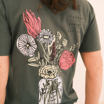Dunkelgrünes T-Shirt mit kurzen Ärmeln. Auf dem Rücken ist ein großes, buntes Blumenarrangement in einem Glas abgebildet. Rechts daneben steht in schwarzer Handschrift der Text: „perhaps nobody but you“.