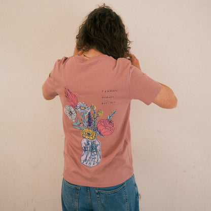 Altrosa T-Shirt mit großem Rückendruck. Der Druck zeigt ein gezeichnetes Bouquet aus verschiedenen Blumen in einer transparenten Vase. Die Blumen sind farbenfroh illustriert in Gelb, Weiß, Rosa, Rot und Blau. Über dem Blumenmotiv steht in handgeschriebener blauer Schrift: „PERHAPS NOBODY BUT YOU.“ Das T-Shirt wird von einer Person getragen, die mit dem Rücken zur Kamera steht. Sie hat lockiges, schulterlanges Haar und trägt eine locker sitzende, hellblaue Jeans. Der Hintergrund ist schlicht und hell.