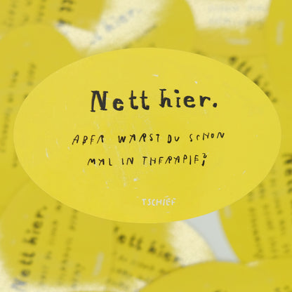 Gelber, ovaler Aufkleber mit schwarzem Schriftzug „Nett hier.“ Darunter handschriftlich ergänzt in Schwarz die Frage: „Aber warst du schon mal in Therapie?“ Unten steht klein „TSCHIEF“. Der Hintergrund zeigt weitere gelbe Aufkleber verschwommen